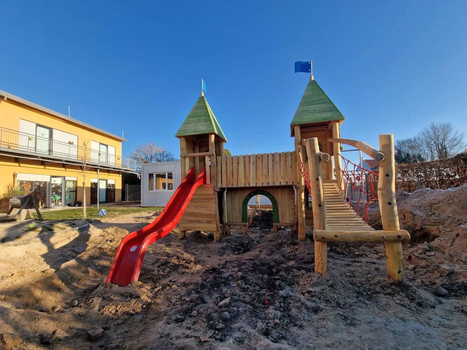 Robinie-Spielanlage mit Edelstahlrutsche vor historischer Halle, montiert von Moshrif Spielplatzbau in Kirn