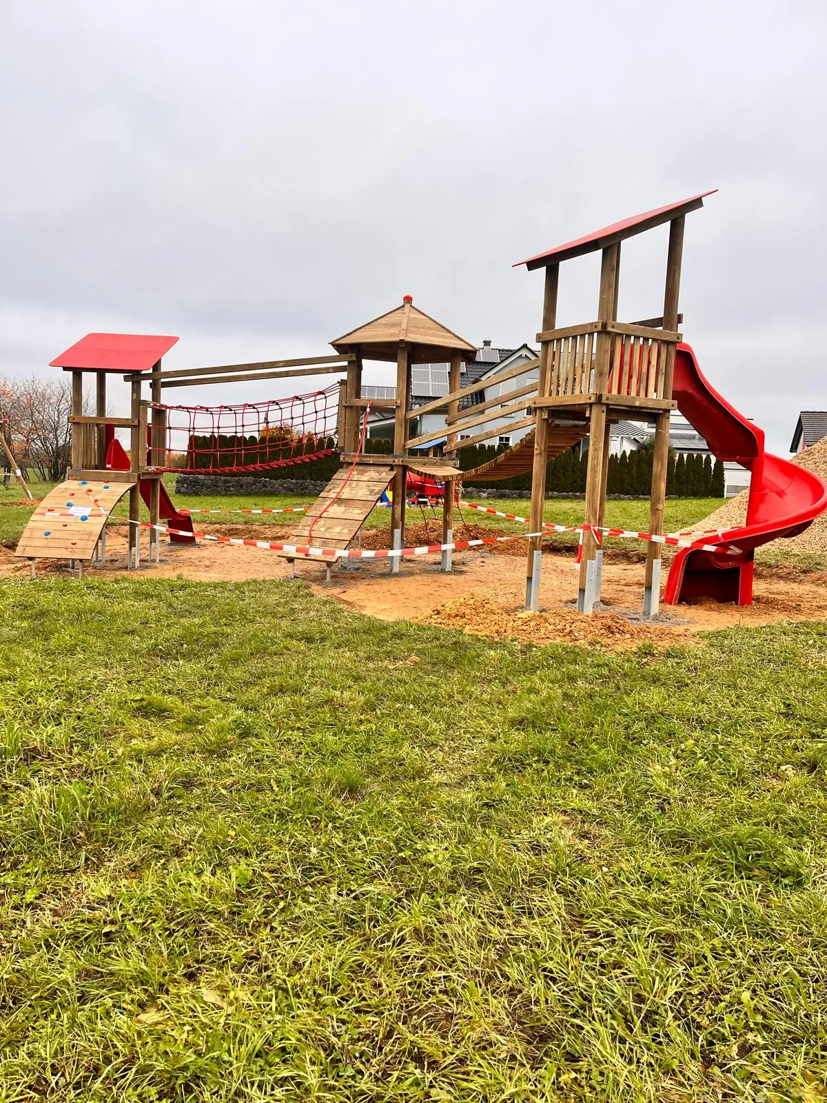 Robinie-Spielturm mit Edelstahlrutsche vor dramatischem Himmel, montiert von Moshrif Spielplatzbau in Friedberg