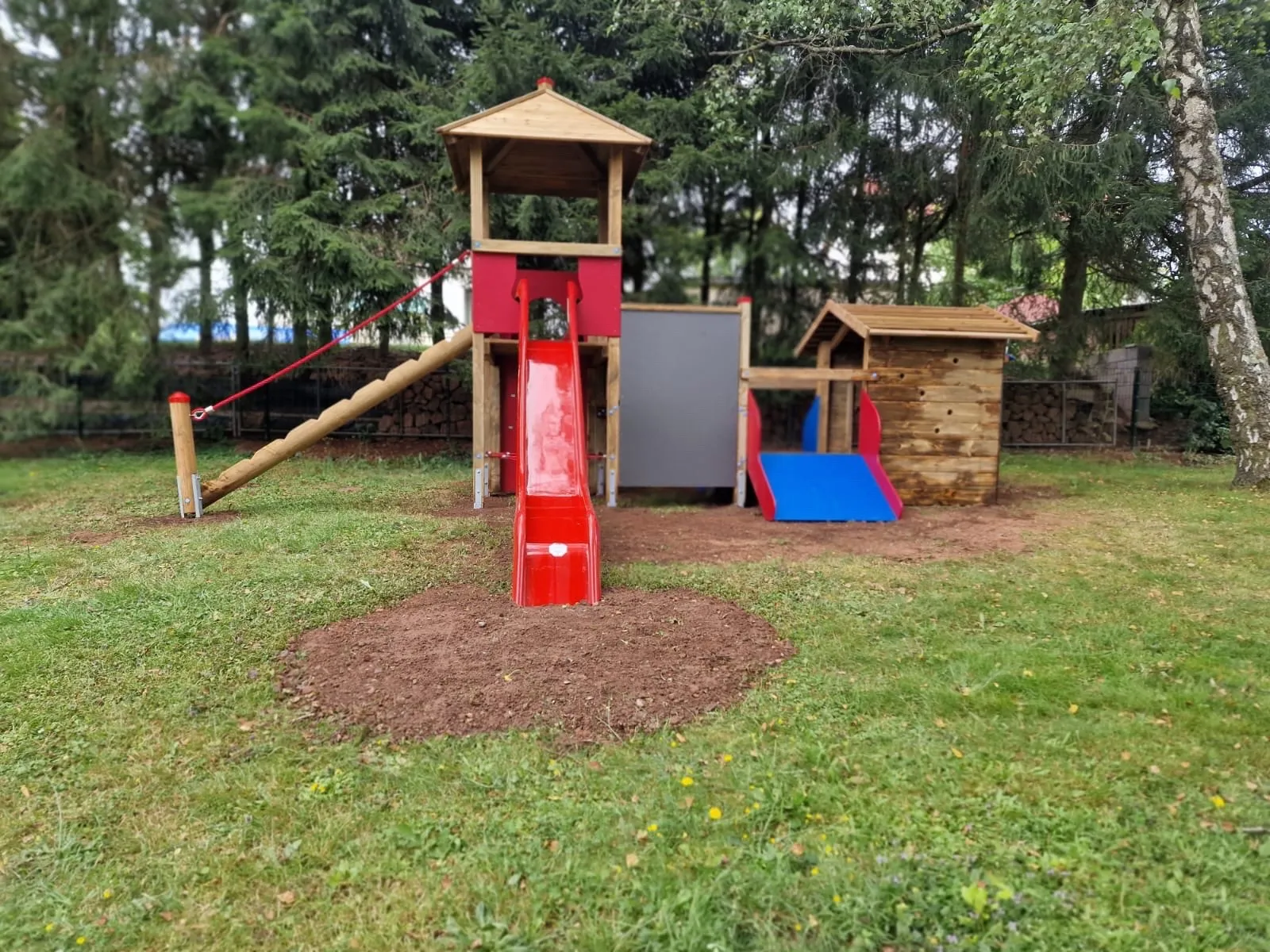 Robinie-Spielturm mit Edelstahlrutsche in einem Neubaugebiet, montiert von Moshrif Spielplatzbau in Nastätten