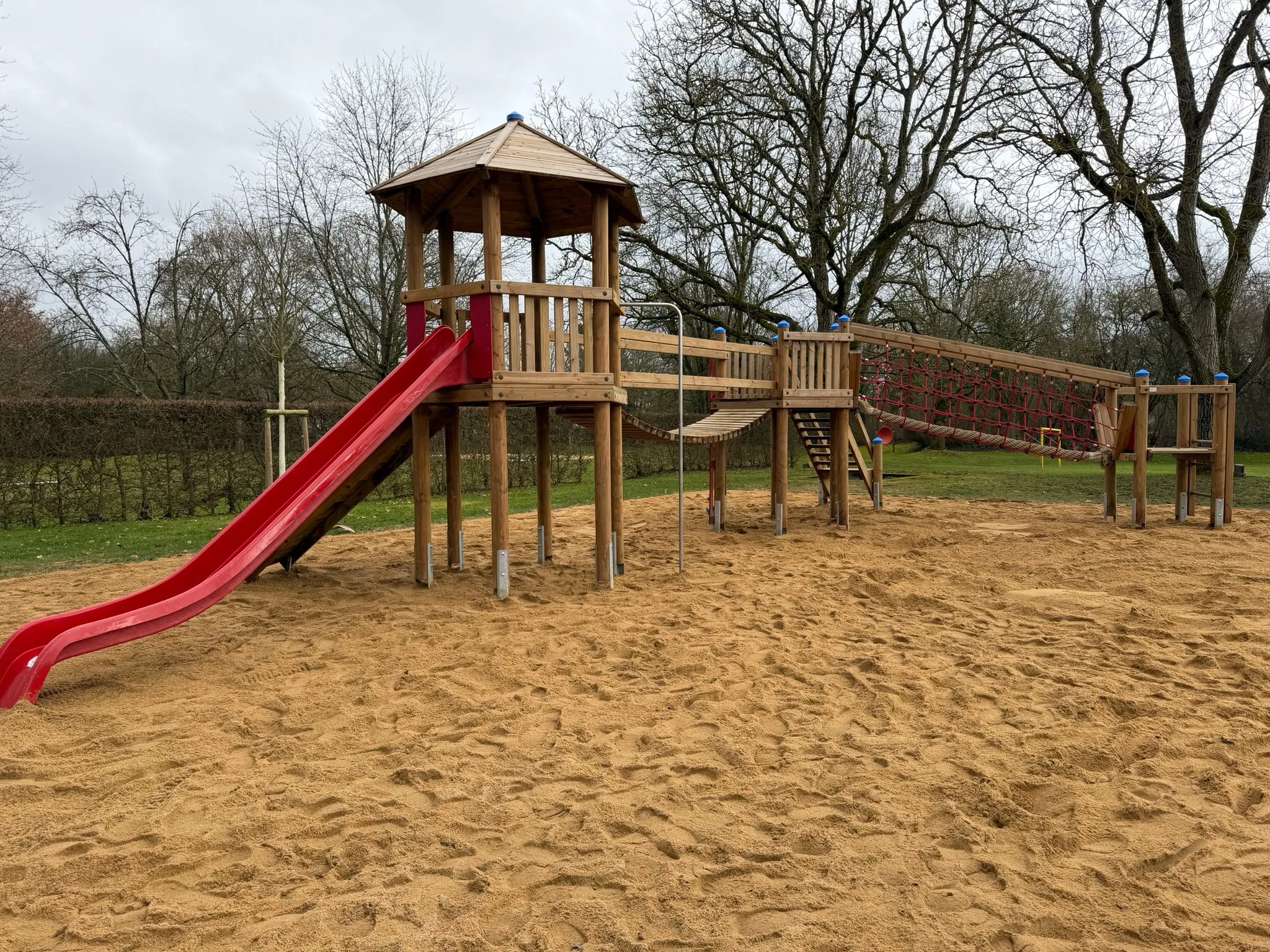 Holz-Spielturm mit Hängebrücke und Rutsche, montiert von Moshrif Spielplatzbau in Leipzig