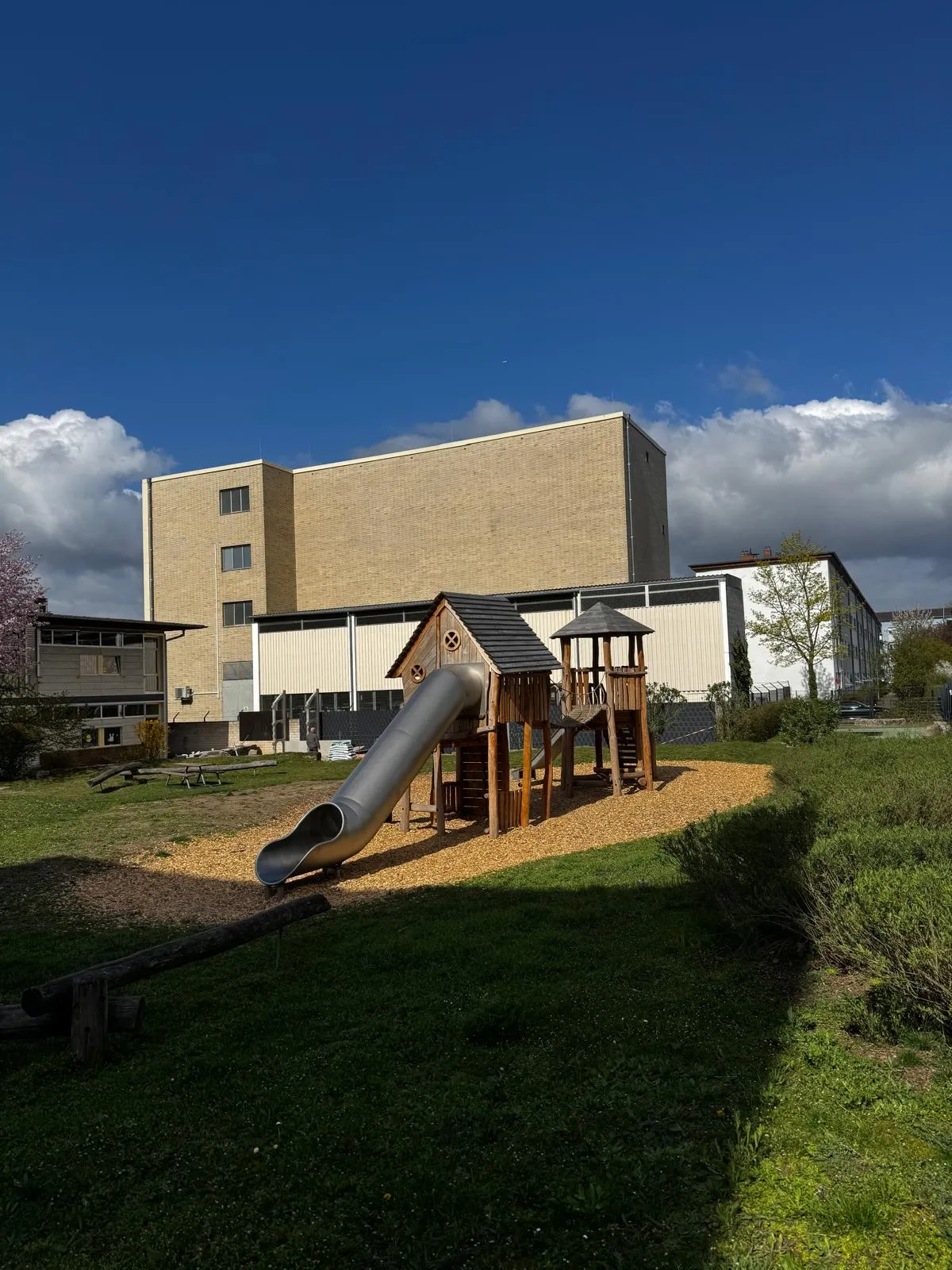 Holz-Spielturm mit Röhrenrutsche auf einem Schulhof, montiert von Moshrif Spielplatzbau in Dortmund