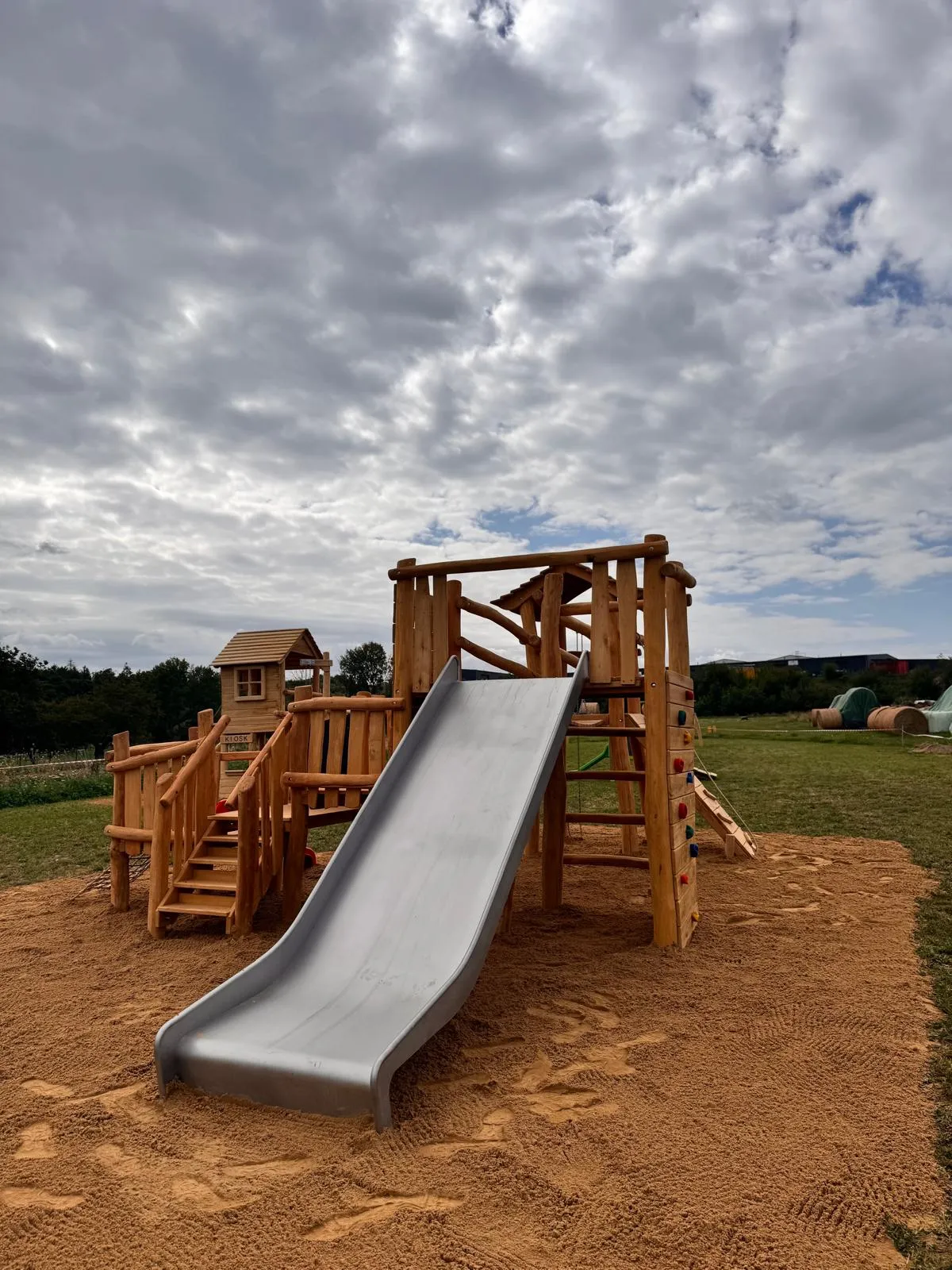 Robinie-Spielturm mit Kletterwand und Edelstahlrutsche in Feldlage, montiert von Moshrif Spielplatzbau in Hannover